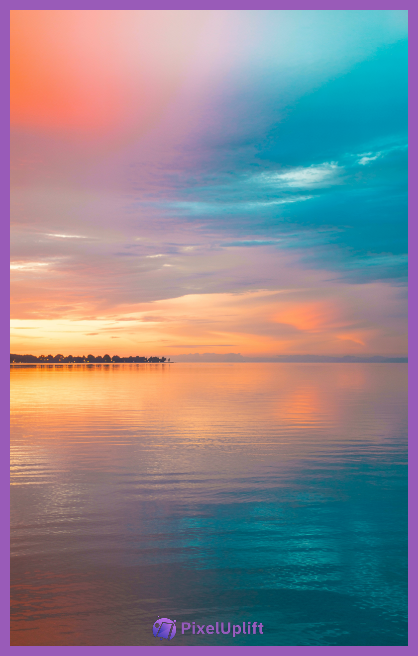Serene sunset over calm water with gradient sky and tree-lined shore silhouette